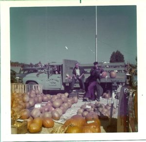 Herb, son John (in the truck cab), son Bruce, and camera-shy Barbara, selling leftover fall vegetables at the 110 Drive-In Flea Market, 1974.