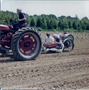 Herb driving the tractor with his wife Mable and son Lee on the setter, planting tree seedlings, 1977.
